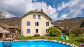 A two-story building with a swimming pool, a slide, and a grassy area with lounge chairs. - Goute la vie  (Marchamp)