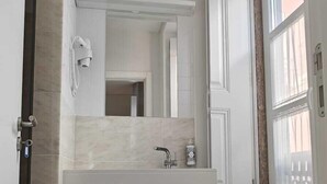 Een moderne badkamer met een marmeren vloer, een witte wastafel en een grote spiegel.