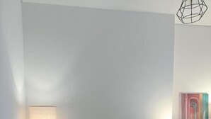 Een woonkamer met een bank, een salontafel, een lamp en een schilderij aan de muur.