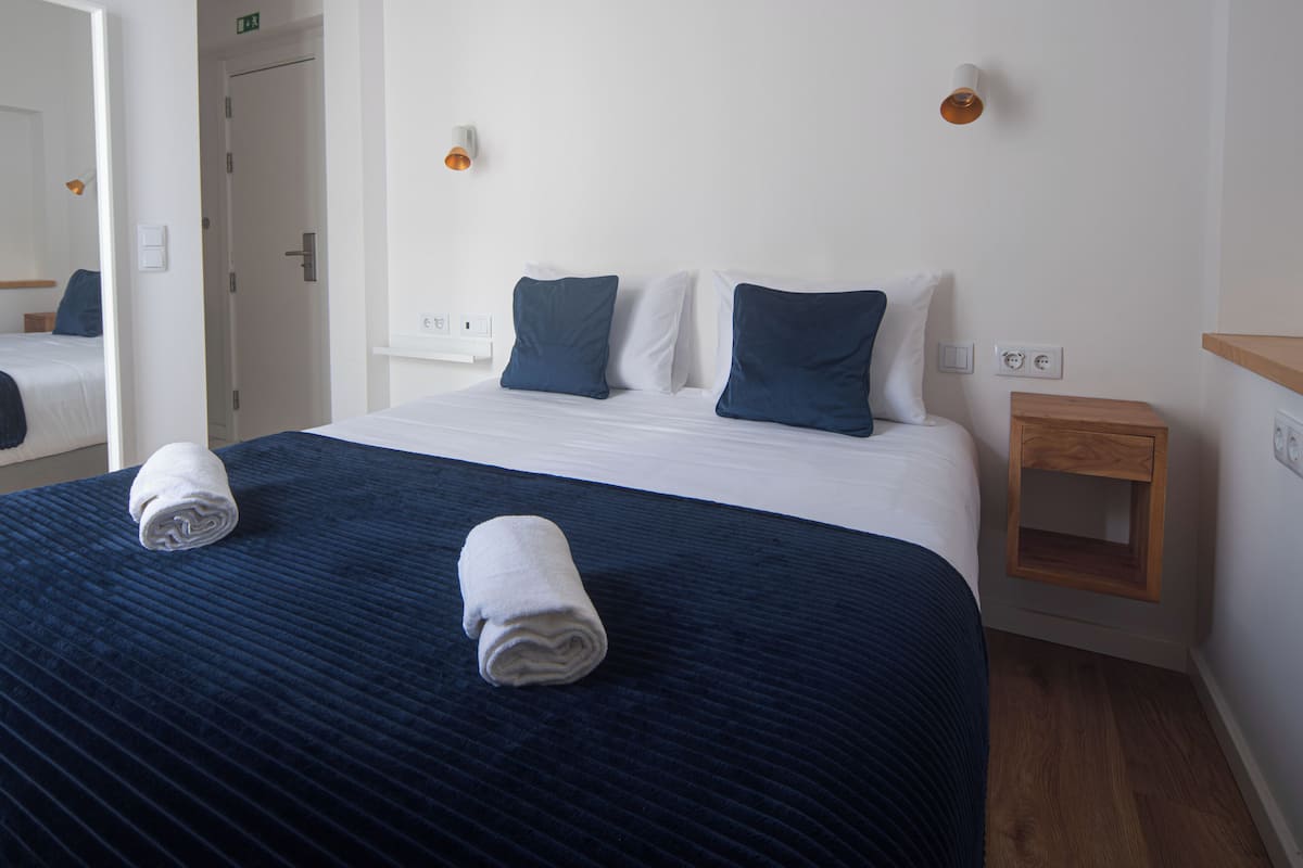 Une chambre d’hôtel avec un grand lit, une table de chevet, un miroir et un appareil de climatisation.
