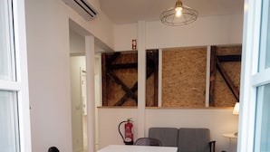 Een ruimtelijk eetgedeelte met een witte tafel, twee stoelen, een brandblusser en een plafondlamp.