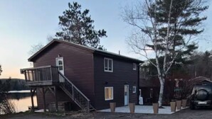 A two-story building with a wooden deck and a staircase leading to a door.