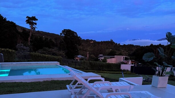 A swimming pool with lounge chairs and a fire pit with green glass pebbles.