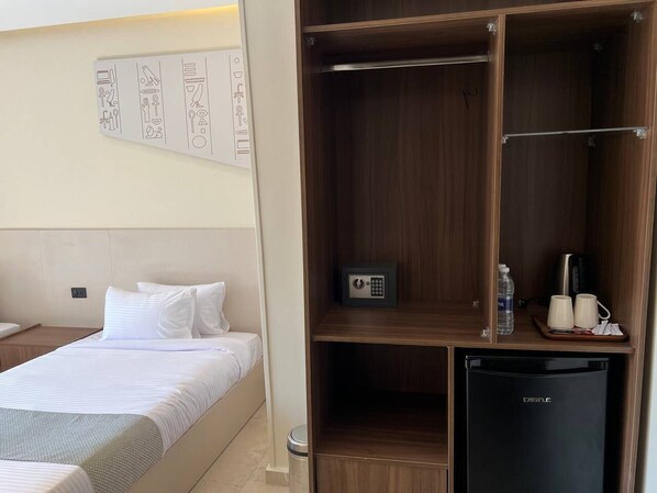 A hotel room with a bed, a wardrobe, a minibar, and a small refrigerator.