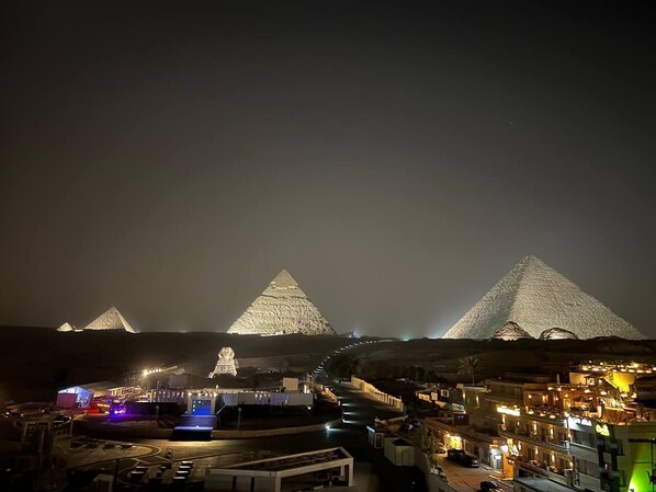 A nighttime view of the pyramids with illuminated structures in the foreground.