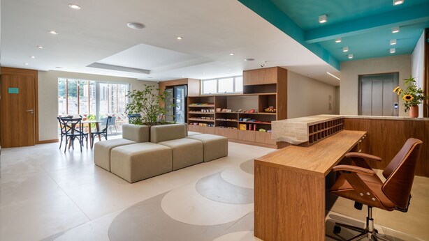 A modern hotel lobby with a wooden reception desk, seating area, and built-in bookshelves.