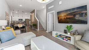 A modern living room with a sofa, coffee table, and a painting on the wall. - Serenity Townhouse! Private Pool and Pet-Friendly (Davenport)