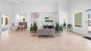 A spacious, modern lobby with a wooden floor, a central seating area with a sofa and chairs, a small table, and a TV mounted on the wall. - Serenity Townhouse! Private Pool and Pet-Friendly (Davenport)