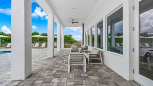 A covered patio area with a pool, outdoor seating, and large windows. - Serenity Townhouse! Private Pool and Pet-Friendly (Davenport)