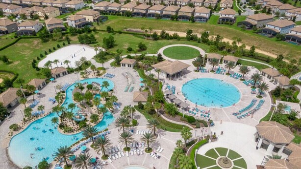Vista aerea di un resort con diverse piscine, lettini e palme.