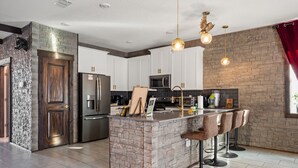 Una cucina moderna con isola centrale, sgabelli da bar e una parete decorativa in pietra.