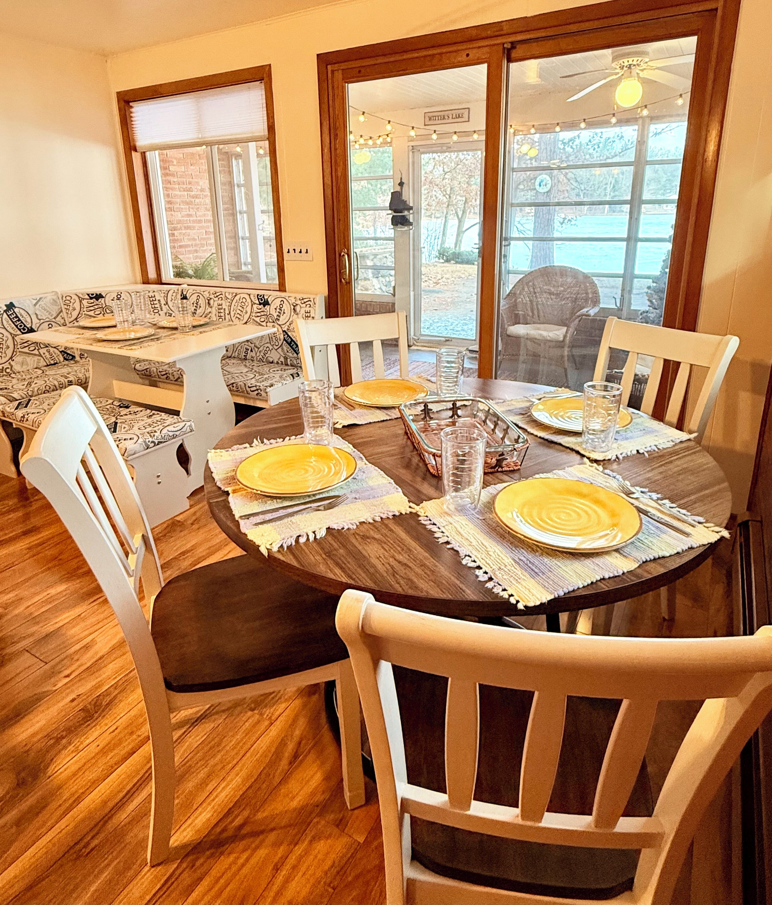 Un espace repas avec une table ronde dressée pour quatre personnes, entourée de chaises en bois.