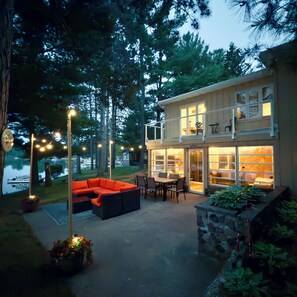 A two-story house with a patio area featuring a sofa and dining table.