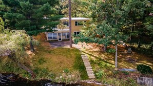 A two-story house with a front yard and a small pond. - Beautiful Lakefront cabin woodburning fireplace, grill, canoe, SUP, AC, parking. (Wautoma)