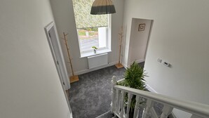 A staircase with a white railing, a potted plant at the top, and a window with a view of the outside. - Sea View – Stunning Three‑Bedroom Apartment with Panoramic Coastal Views (Eastbourne)