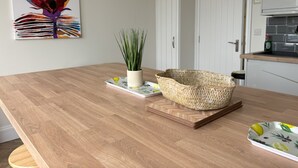 A wooden dining table with a woven basket and a potted plant. - Sea View – Stunning Three‑Bedroom Apartment with Panoramic Coastal Views (Eastbourne)