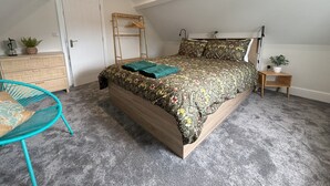 A bedroom with a bed, a dresser, a chair, and a small table with a plant. - Sea View – Stunning Three‑Bedroom Apartment with Panoramic Coastal Views (Eastbourne)