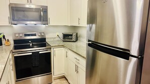 Una cocina con refrigerador de acero inoxidable, microondas, horno y tostadora.