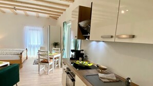 A modern kitchen with a built-in oven, a sink, and a dining area with a table and chairs. - Schönes helles Studio-Appartement mit großem Balkon (Engelsbrand)