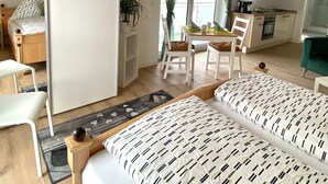 A cozy room with two beds, a small kitchenette, and a dining area. - Schönes helles Studio-Appartement mit großem Balkon (Engelsbrand)