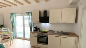 A compact kitchen with a built-in oven, a coffee maker, and a sink. - Schönes helles Studio-Appartement mit großem Balkon (Engelsbrand)
