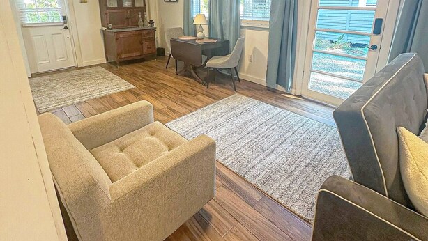 Een ruime woonkamer met een bank, een salontafel en een eethoek met een kast en stoelen.