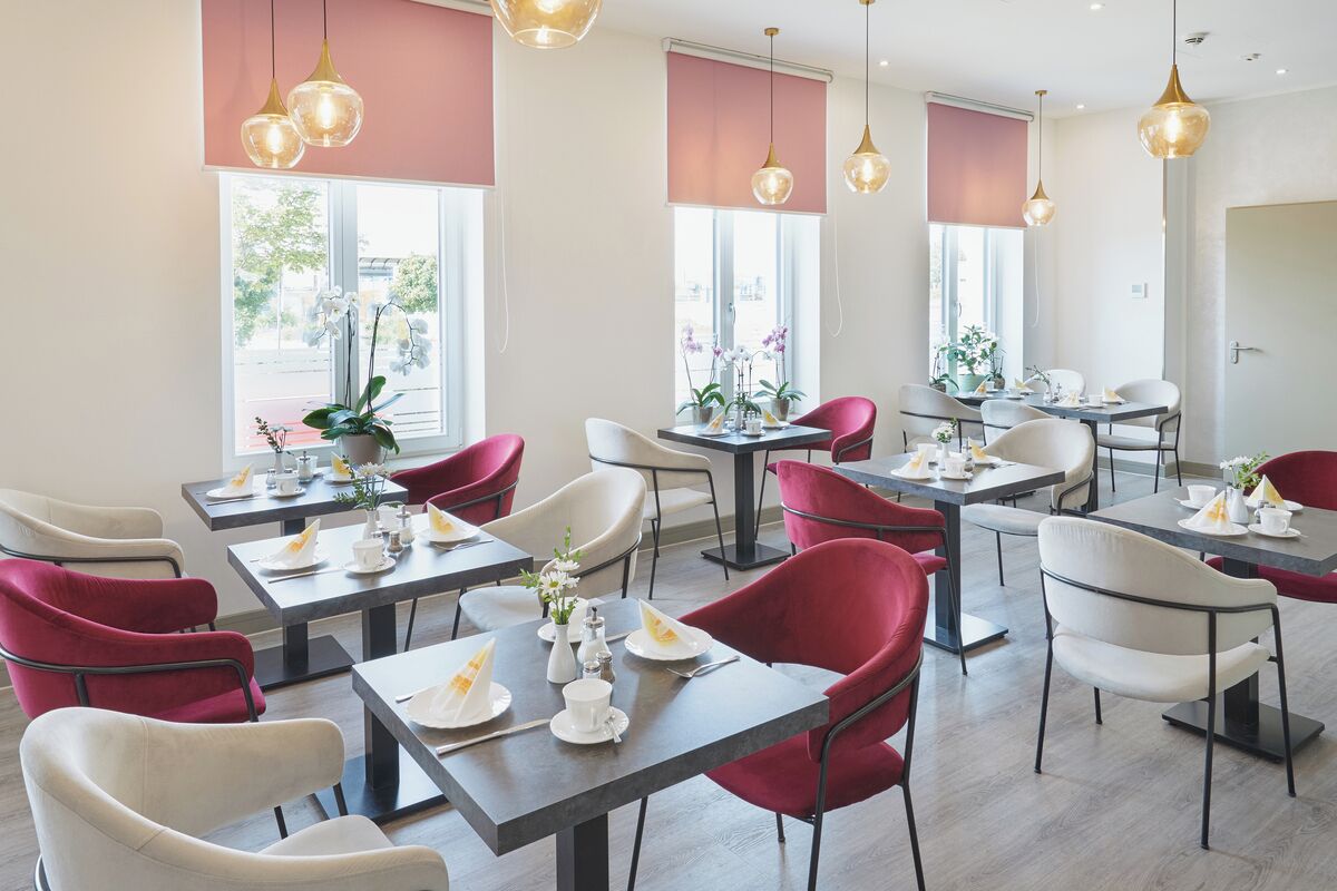 A modern dining area with tables and chairs, large windows, and hanging pendant lights.