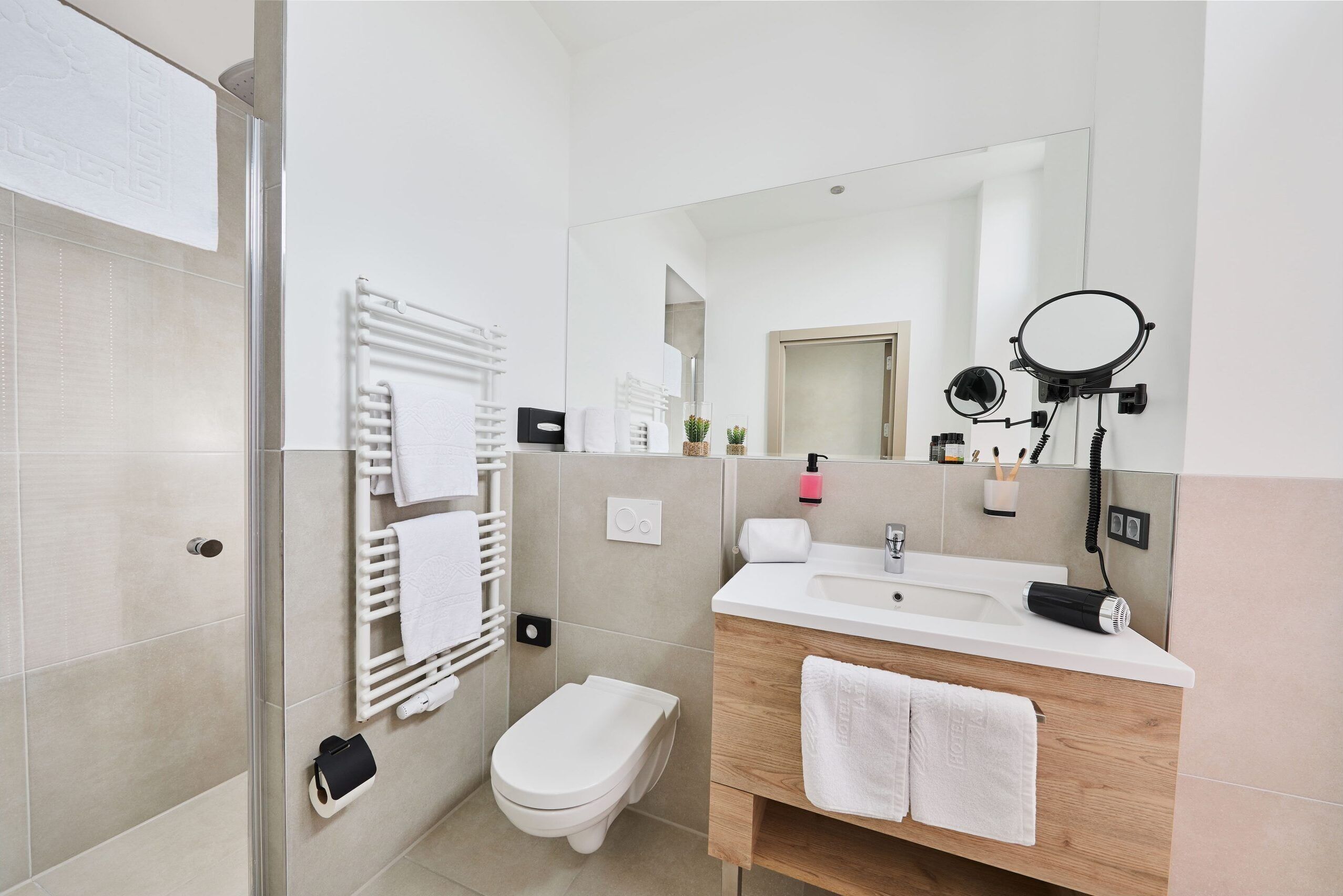 Een moderne badkamer met een wit toilet, een wastafel met spiegel en een handdoekrek.