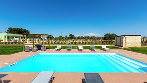 Une piscine avec des chaises longues et un espace abrité.