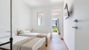 Une chambre d’hôtel avec deux lits simples, un plancher en bois, un grand miroir et une porte donnant sur un balcon.