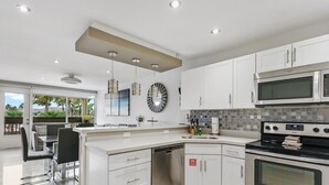 Una cucina moderna con mobili bianchi, elettrodomestici in acciaio inossidabile e una grande isola con posti a sedere.