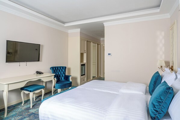 Une chambre d’hôtel avec un grand lit, un bureau avec une chaise, une télévision et une porte donnant sur une autre pièce.