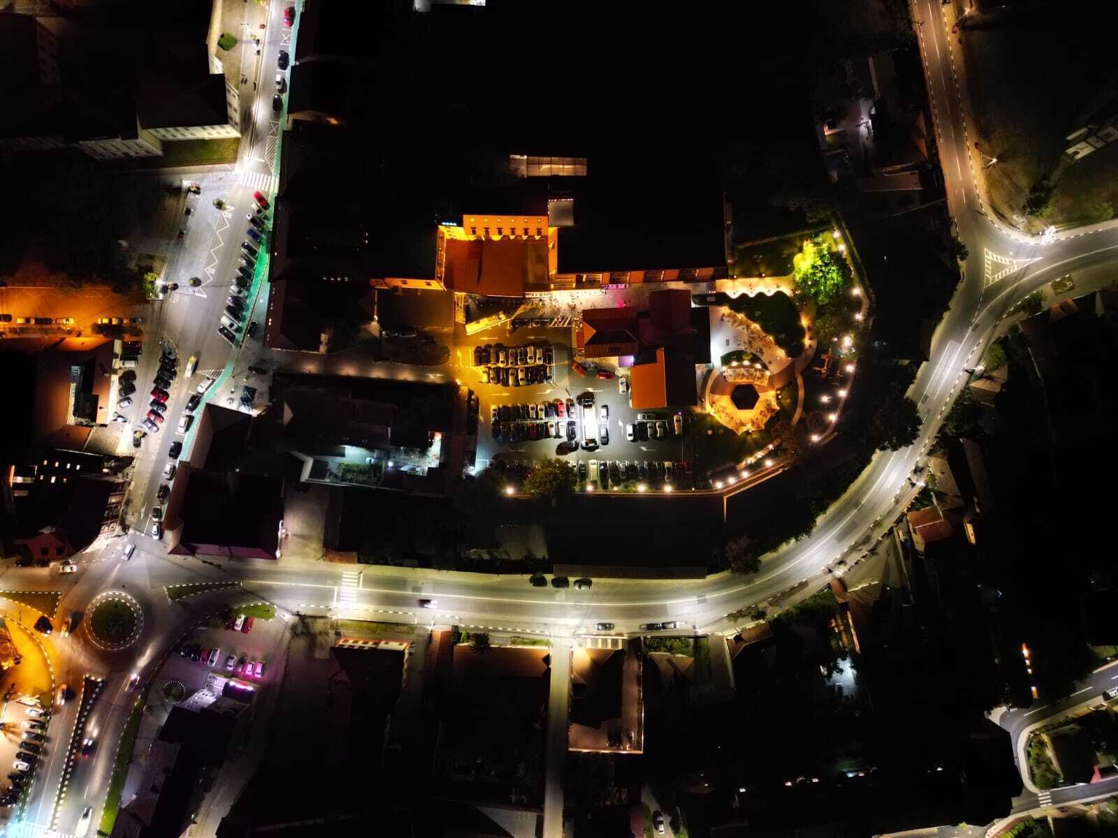 An aerial view of a hotel with a central courtyard, multiple parking areas, and a roundabout.