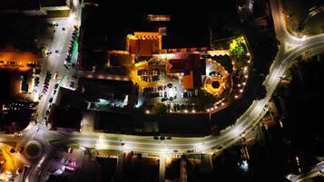 An aerial view of a hotel with a central courtyard, multiple parking areas, and a roundabout.