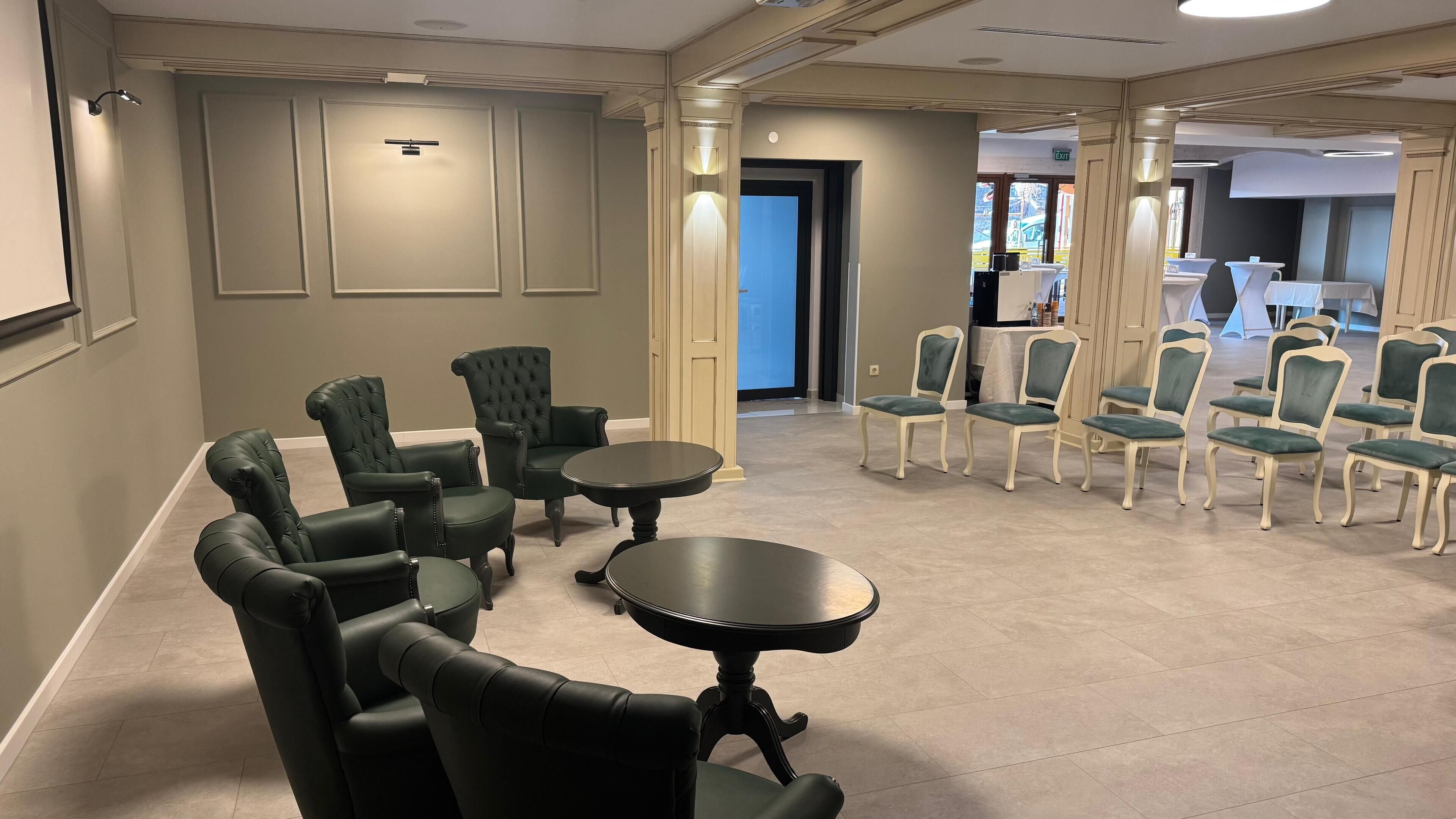 Une salle de conférence avec une longue table et plusieurs chaises, une porte donnant sur l’extérieur, et une petite table avec des chaises au premier plan.
