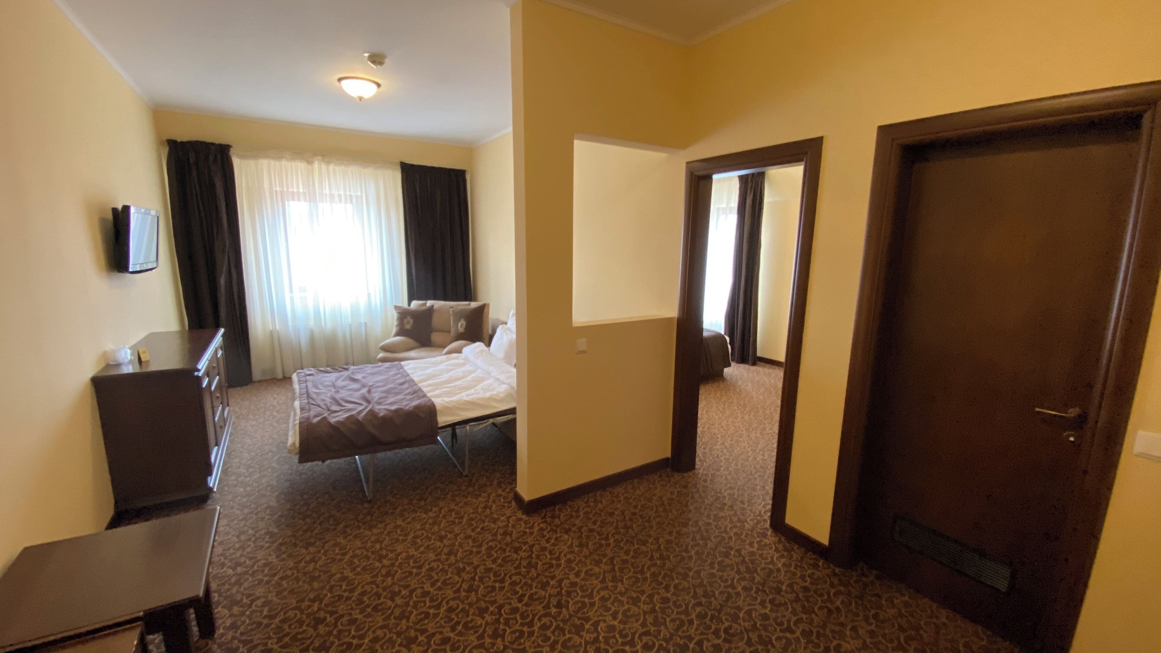 Una habitación de hotel con cama, escritorio, silla, armario y puerta.