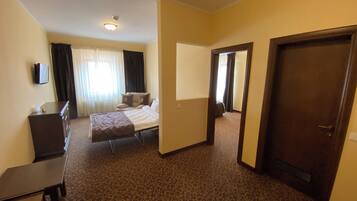 Una habitación de hotel con cama, escritorio, silla, armario y puerta.