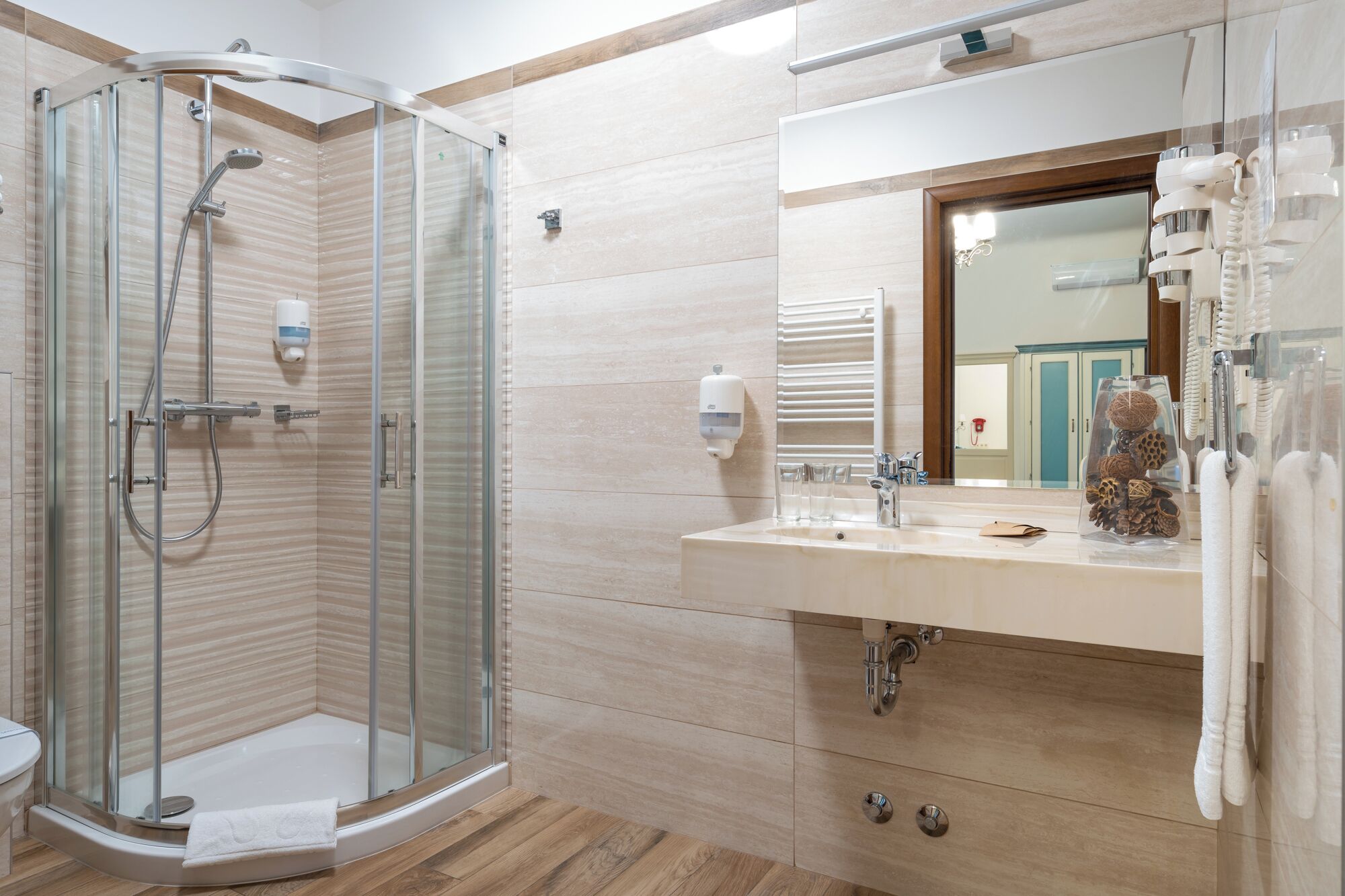 A modern bathroom with a glass-enclosed shower, a vanity with a mirror, and a towel rack.