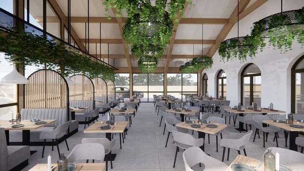 A spacious restaurant with high ceilings, hanging plants, and a modern interior design.