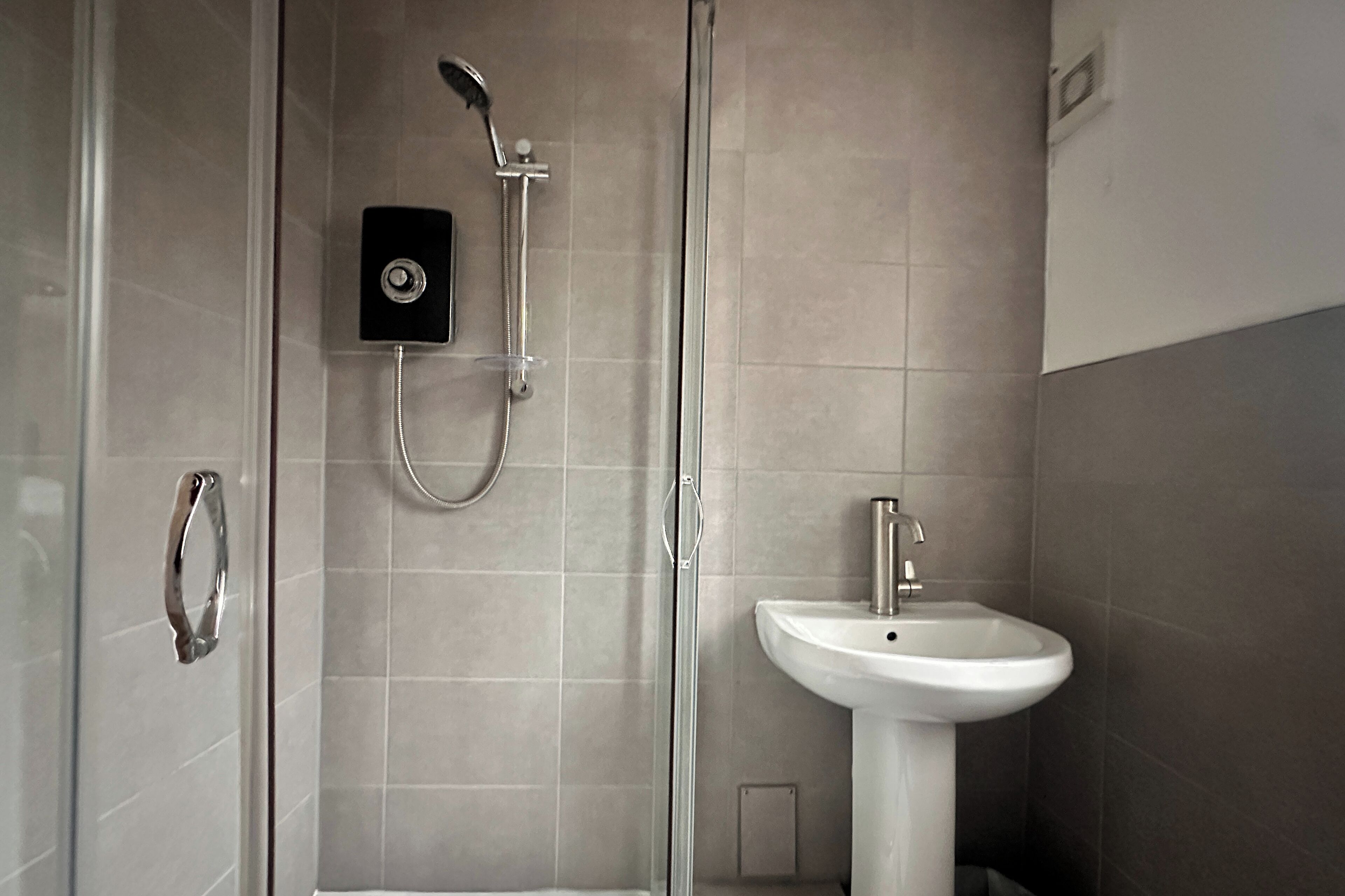 Un baño moderno con cabina de ducha de vidrio, lavabo empotrado y panel de control para la ducha.