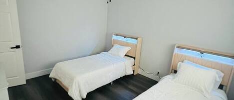 A bedroom with two single beds, a ceiling fan, and a white wardrobe.