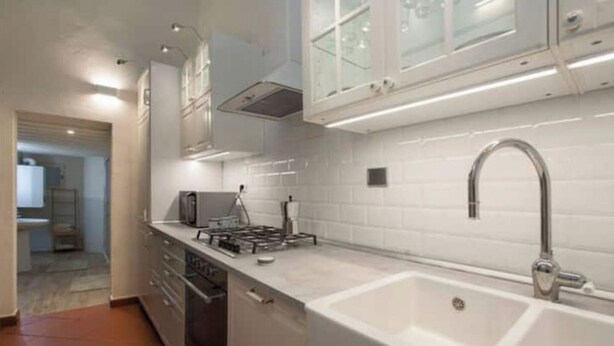 A modern kitchen with white cabinetry, a stainless steel sink, and a gas stove. - Historic Palazzo, Central Location, 3 bedrooms retreat. Best Florence Booking (Firenze)