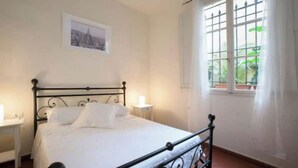 A bedroom with a bed, a nightstand, a window with curtains, and a framed picture on the wall. - Historic Palazzo, Central Location, 3 bedrooms retreat. Best Florence Booking (Firenze)