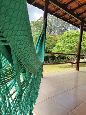 A hammock hanging under a wooden structure with a tiled floor and a view of a grassy area and trees. - Country house in Extrema with natural water pool, we accept pets (Itapeva)