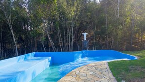 A swimming pool with a stone pathway leading to a white statue.