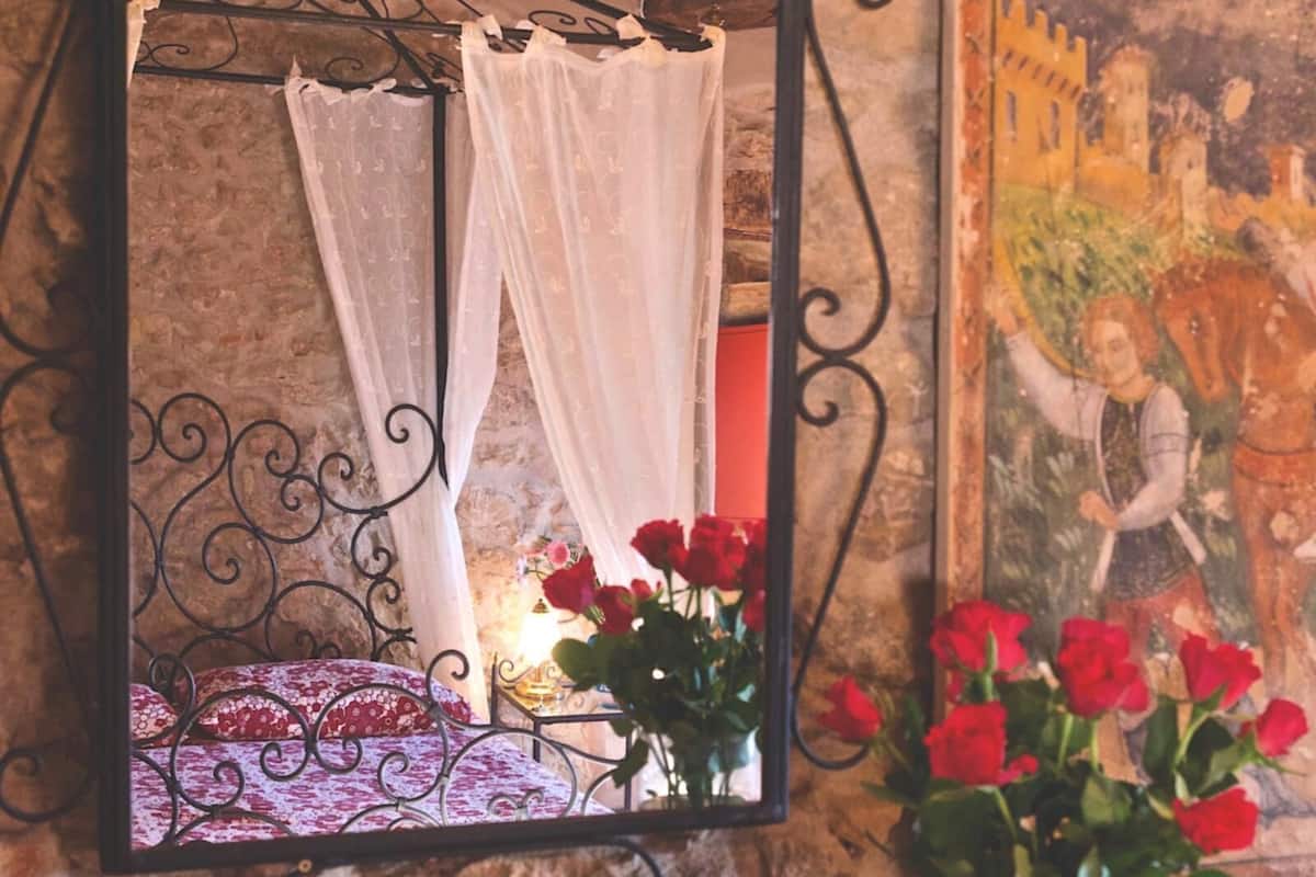 Una cama con dosel blanco y rosas rojas a un lado.