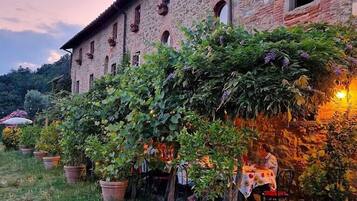 A stone building with a garden area featuring potted plants and a table with chairs.