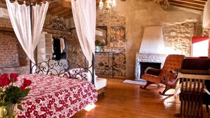 Une chambre à coucher rustique avec un lit à baldaquin, une cheminée en pierre et un plancher en bois.