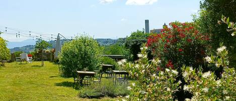 A garden with outdoor seating, a view of the countryside, and a building in the background.
