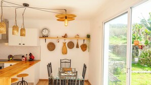 A kitchen with a wooden countertop, hanging woven light fixtures, and a dining area with a glass table and chairs. - Candelaria House (Candelária)